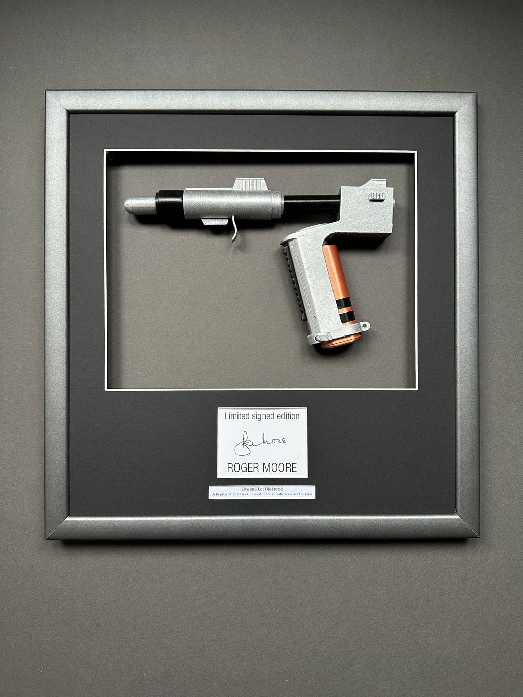 A James Bond Movie Prop Replica in a bespoke Framed Display with an autograph of Roger Moore.